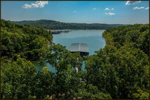 Lakefront view framed by trees with a small covered dock and calm blue water