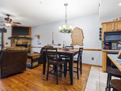 Dining area and kitchen corner in a condo with wood floors, stone fireplace, and high-top table